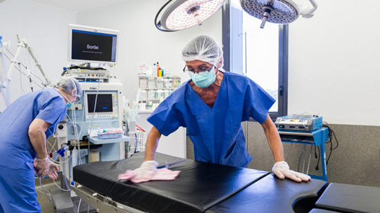 Zwei Personen reinigen einen Operationssaal in einem Krankenhaus