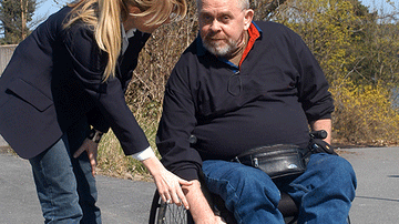 Mann im Rollstuhl mit weiblicher Hilfskraft