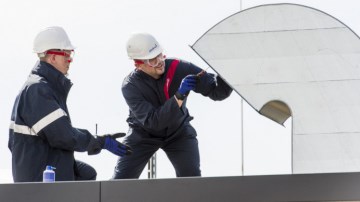 Zwei Männer sind handwerklich auf einem Dach tätig