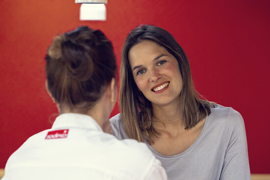 Une femme souriant à une employée Sodexo tournée de dos