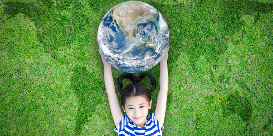 Petite fille allongée sur une pelouse, tenant un globe terrestre