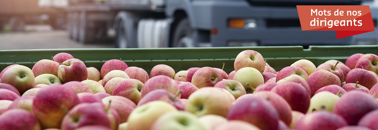 Caisse de pommes avec un camion en arrière-plan, texte: mots de nos dirigeants