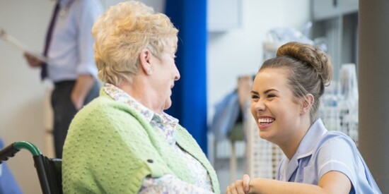 young woman smiling at a lady in a wheelchair