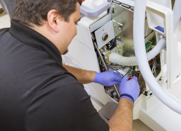 A man in a black shirt expertly repairs a machine