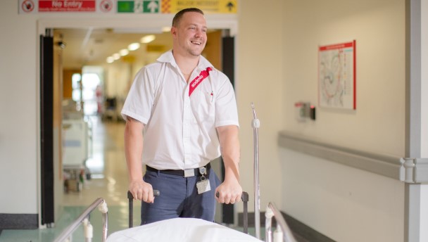 man pushing a gurney in a hallway and smiling