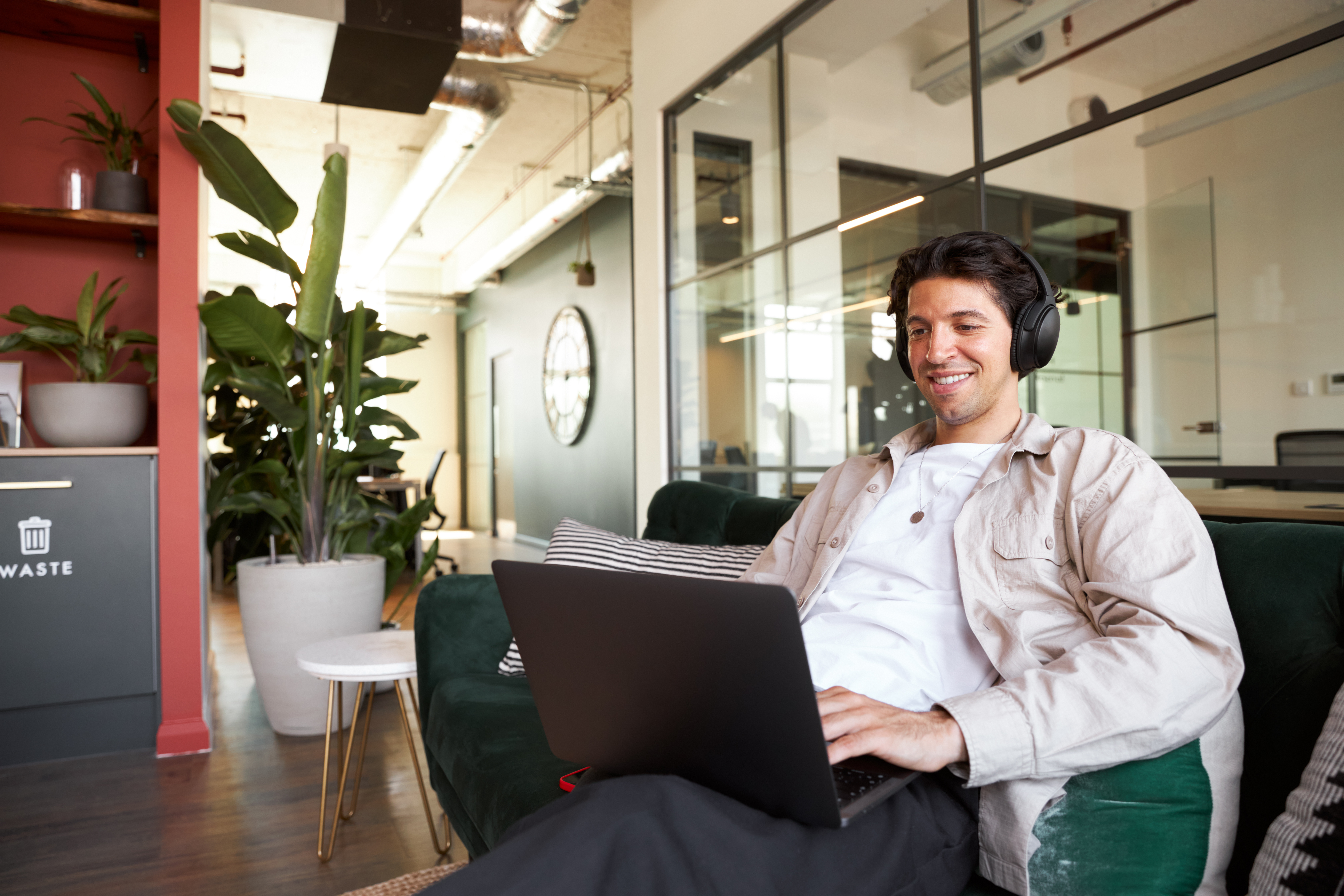 employee sitting on a couch with computer and headphones