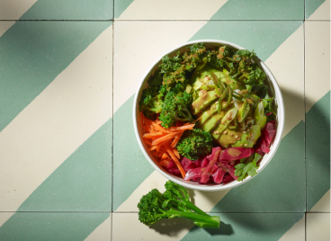 A bowl filled with various vegetables, including a single piece of broccoli