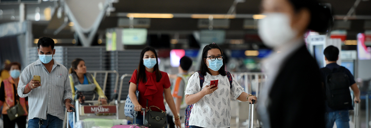 people walking through an airport wearing facemasks