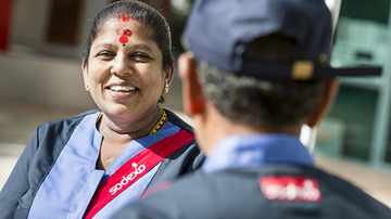 Indisk kvinna som ler mot en man som man ser nacken på