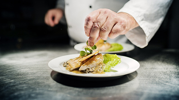 Chef adding a garnish to a dish of food