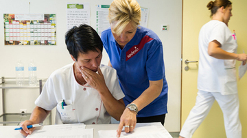 A sodexo employee showing a hospital employee something on a piece of paper