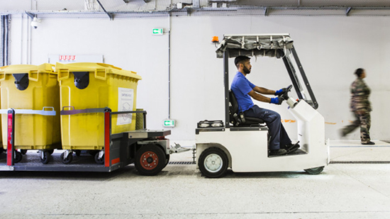 Un employé Sodexo conduit un petit camion pour déplacer des poubelles