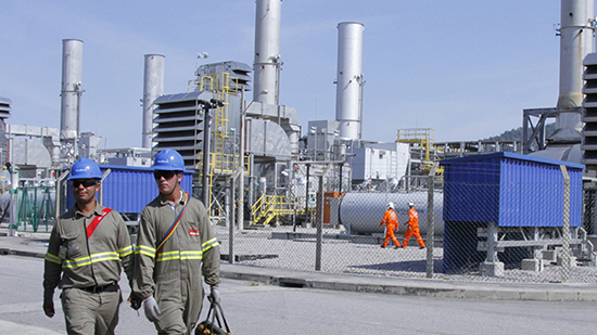 Two sodexo employees in protective clothing in front of a power plant