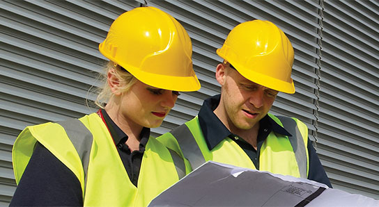 Woman and man in hard hats looking at construction plans